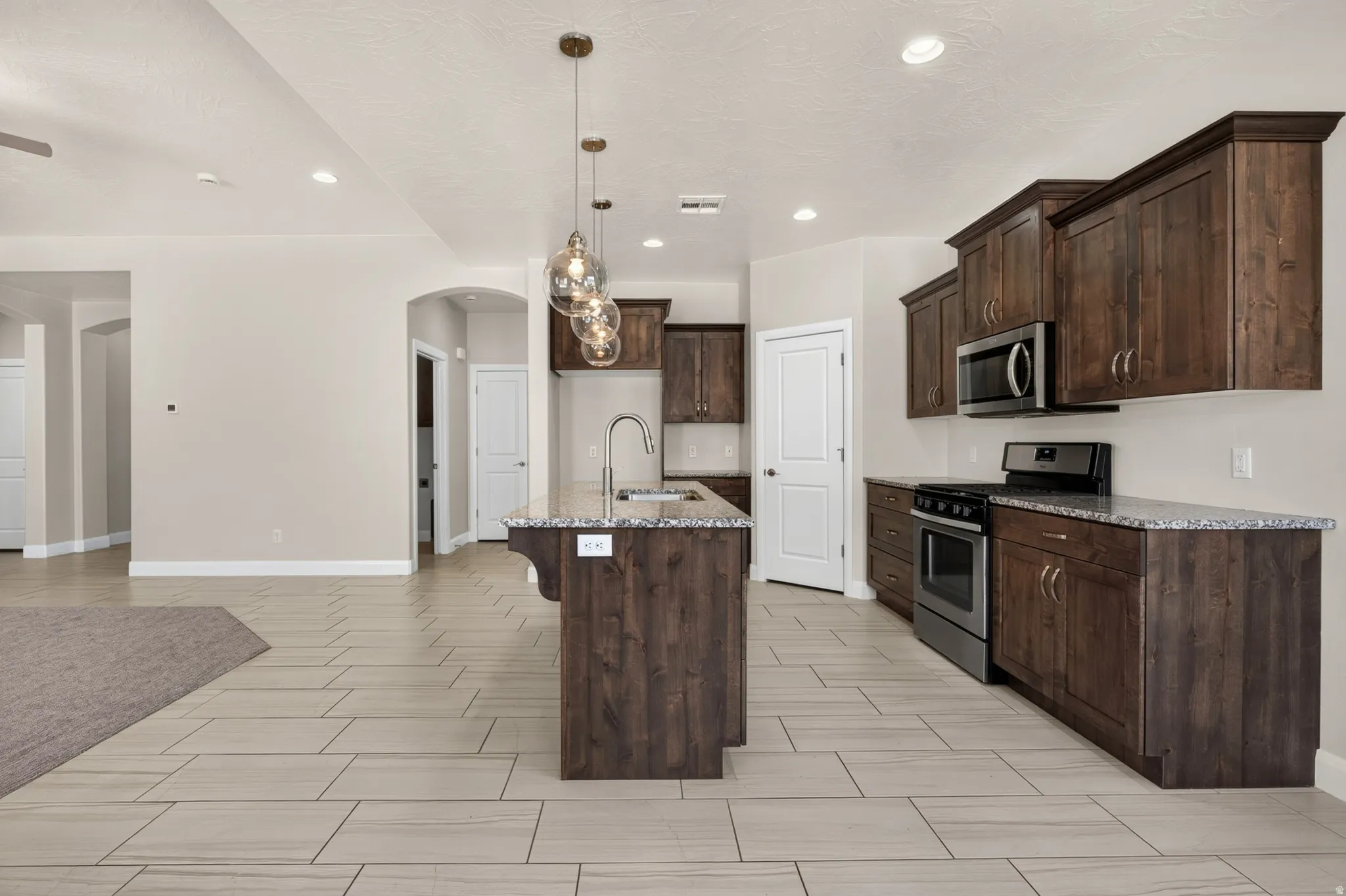 Kitchen featuring rich wood cabinetry, stainless steel appliances, granite countertops, and an island with a breakfast bar