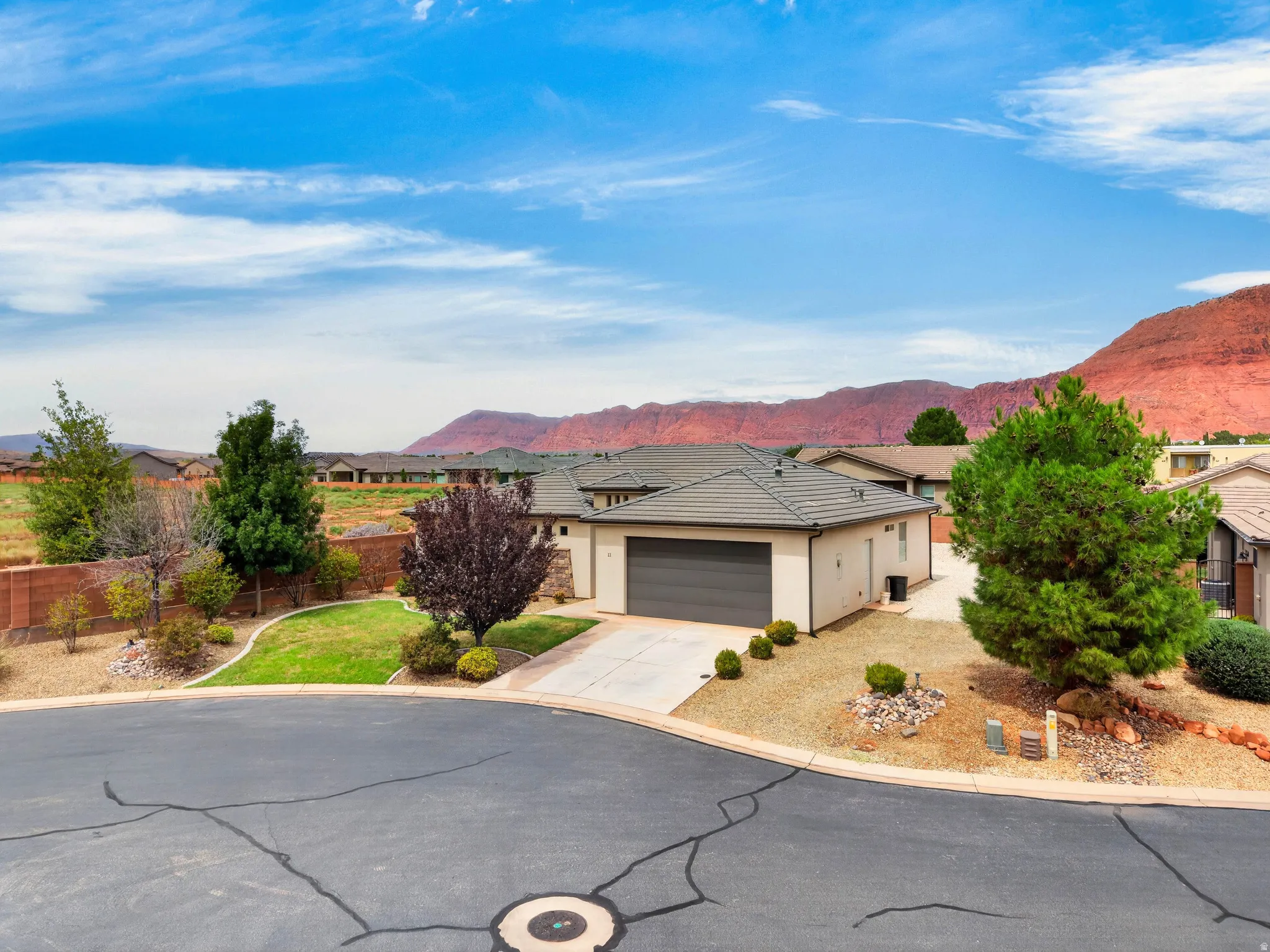 Single-story residence featuring a two-car garage, concrete driveway, and a stone-tiled roof