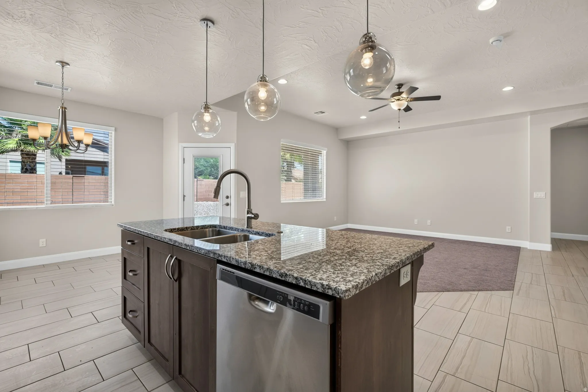 Kitchen island with granite countertop, integrated double basin sink, and stainless steel dishwasher