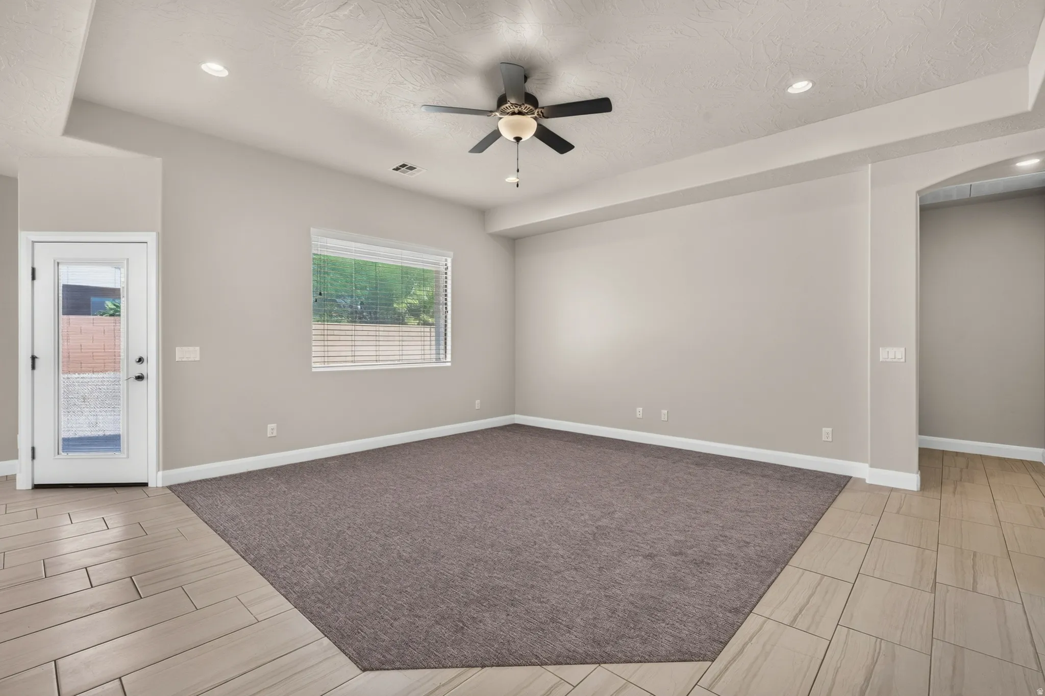 Spacious room featuring a ceiling fan with integrated lighting, recessed lighting, and a large window with blinds
