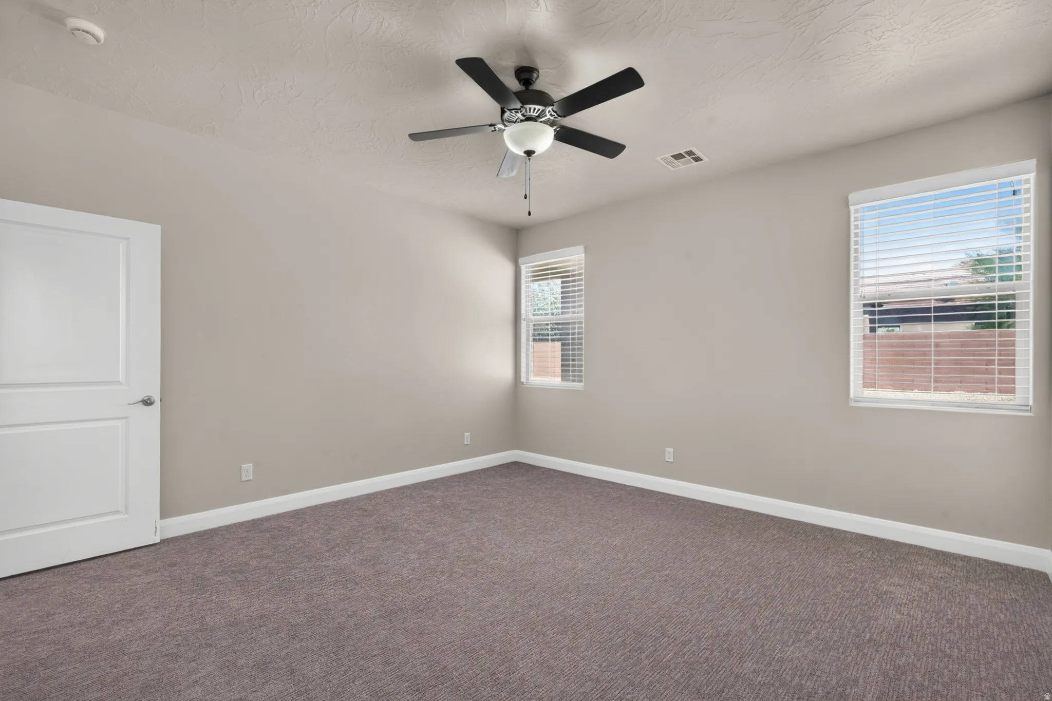 Neutral-toned walls, textured ceiling, and gray-patterned carpet