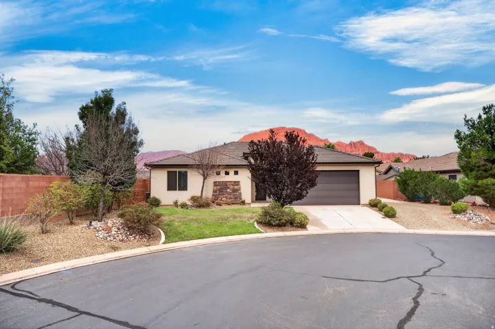 Single-story residence featuring a two-car garage, stucco exterior, and stone accents
