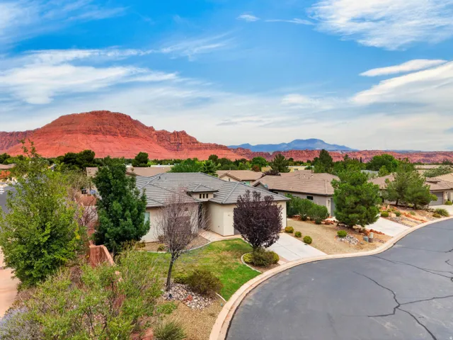 Red rock mountain backdrop, residential neighborhood setting, curved street, concrete driveways, mature landscaping