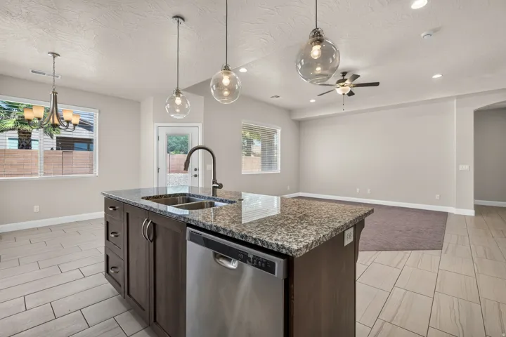 Kitchen island with granite countertop, integrated double basin sink, and stainless steel dishwasher