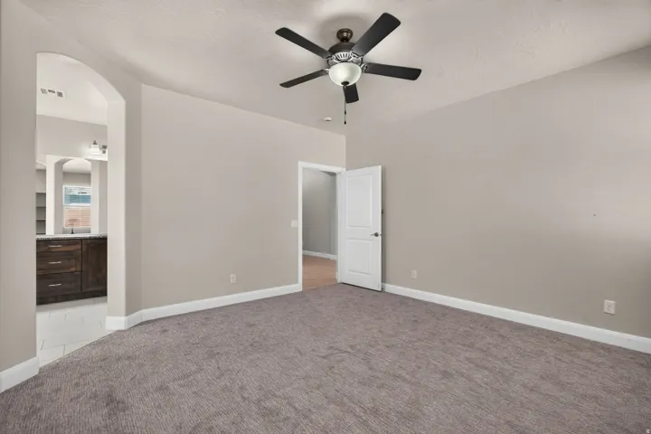 Arched entryway leading to an interior space with dark wood-finish cabinetry, a built-in ceiling fan, and light gray wall tones