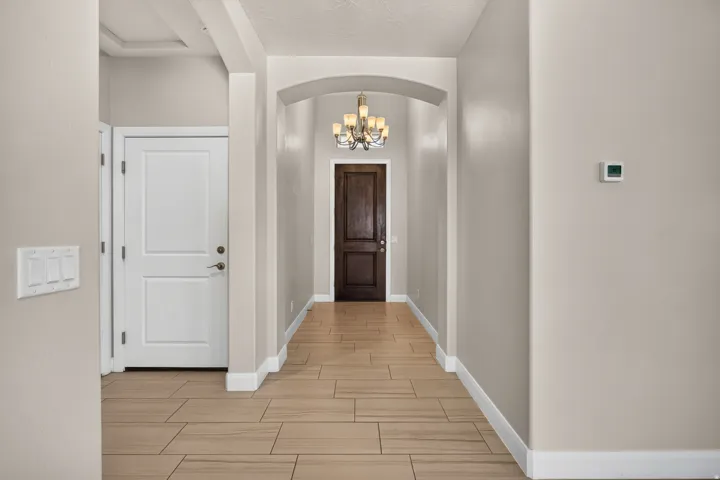 Hallway featuring wood-look tile flooring, an arched entryway, and a decorative chandelier