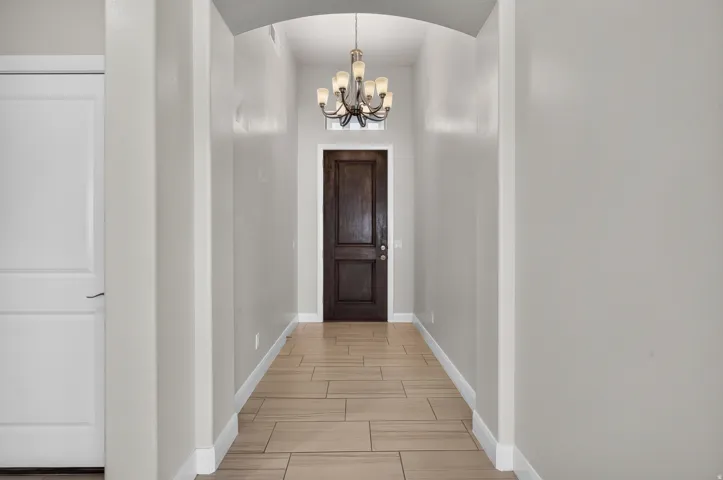 Arched entryway featuring wood-finish tile flooring and a decorative chandelier