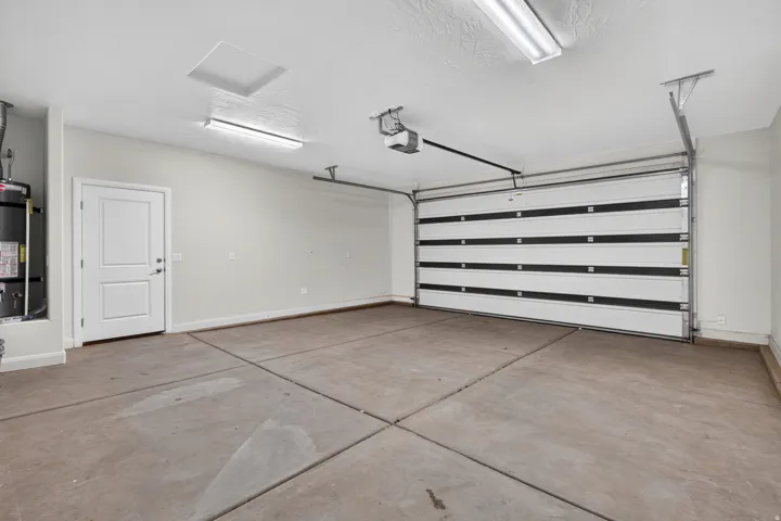 Attached garage featuring a white paneled door, concrete flooring, and ceiling-mounted lighting