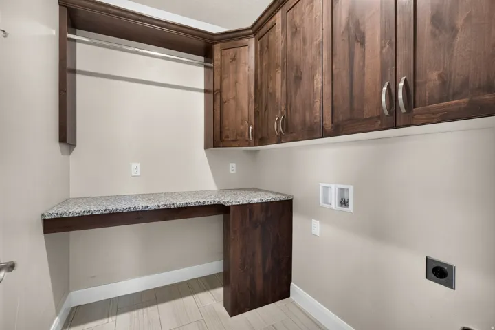 Wall-mounted wood-finish cabinetry, granite-style countertop, integrated hanging rod, and light wood-finish flooring