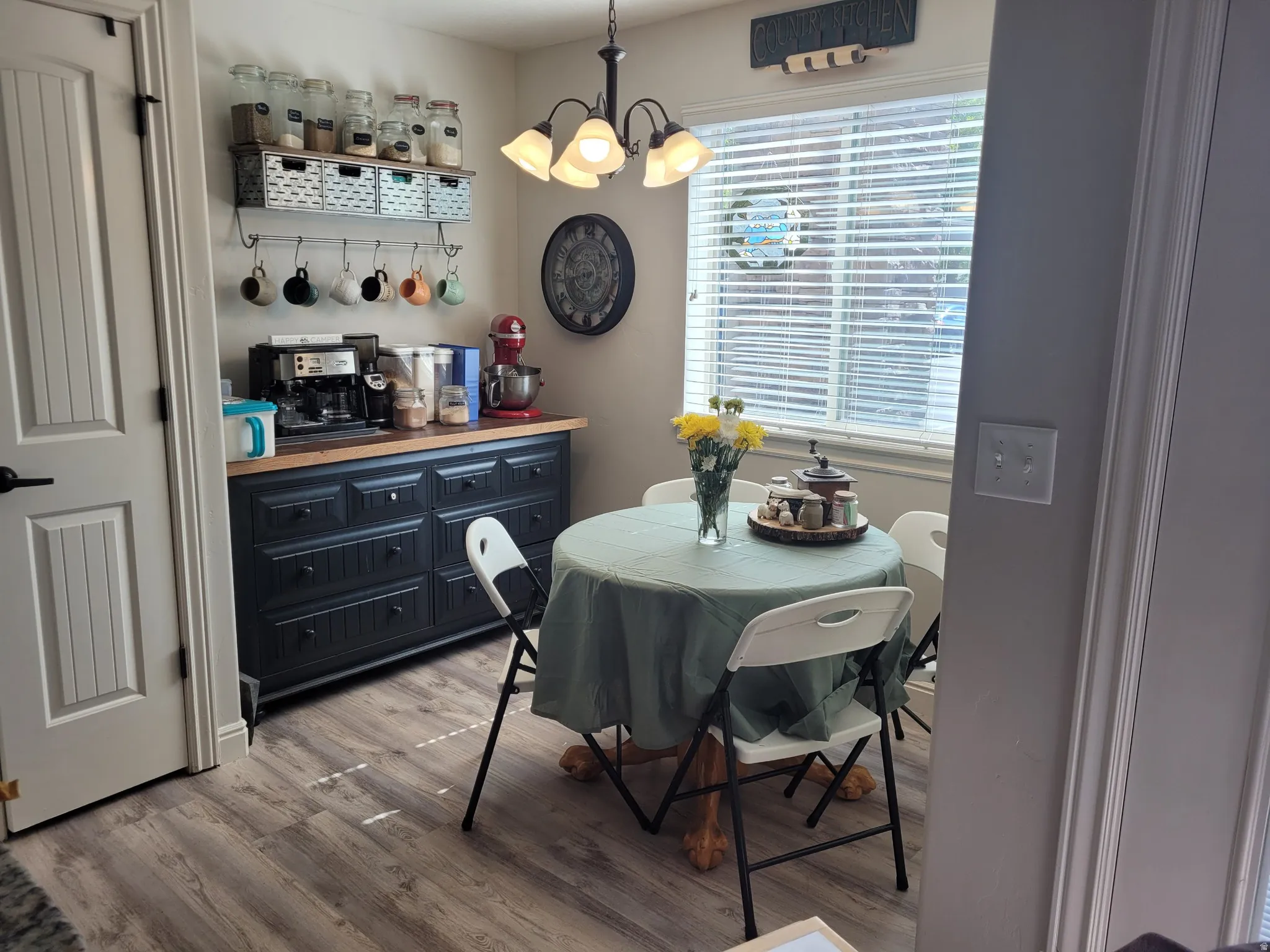 Wood-finish flooring with a decorative light fixture, built-in storage cabinet, and a window with blinds