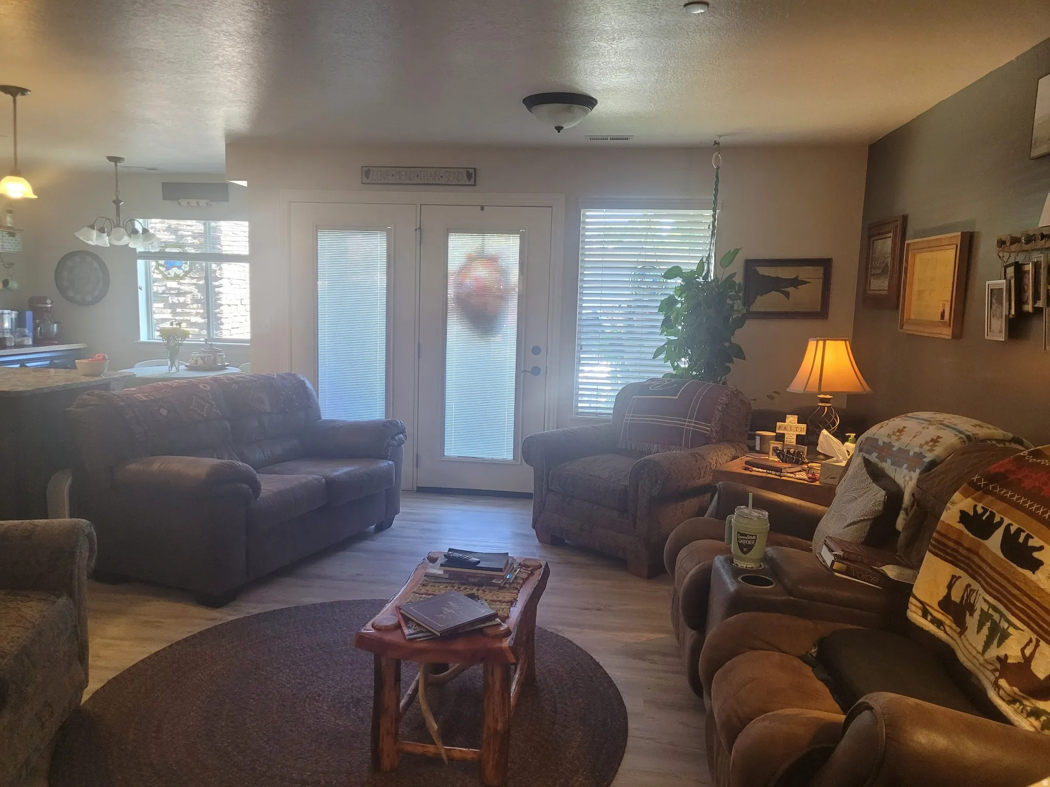 Open-concept living area with wood-finish flooring, featuring a double-door entry with frosted glass panels, and a recessed window