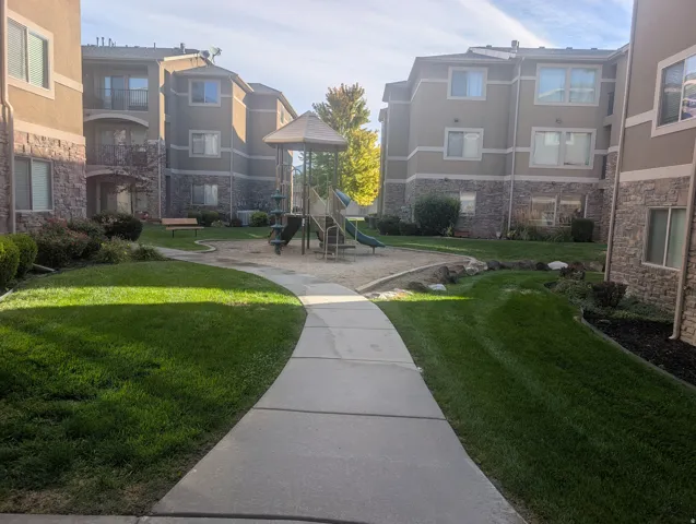 Community courtyard featuring a playground, established lawn, and paved walkways