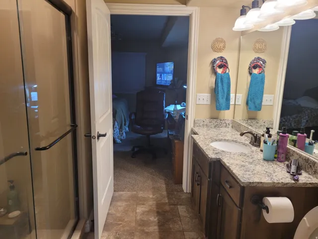 Vanity with a granite-style countertop, undermount sink, and dark wood cabinetry