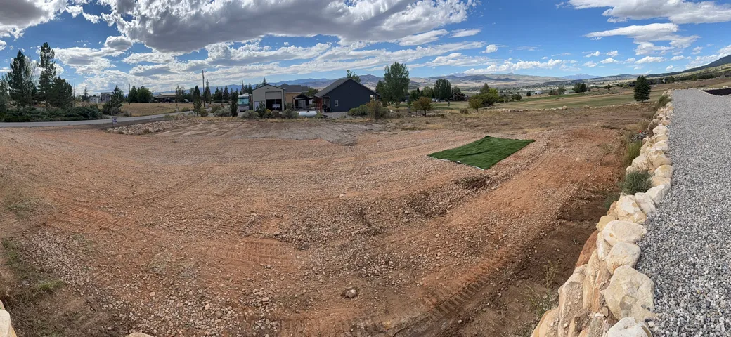 Graded lot featuring a gravel hardscaping element, a stone retaining wall, and distant natural scenery