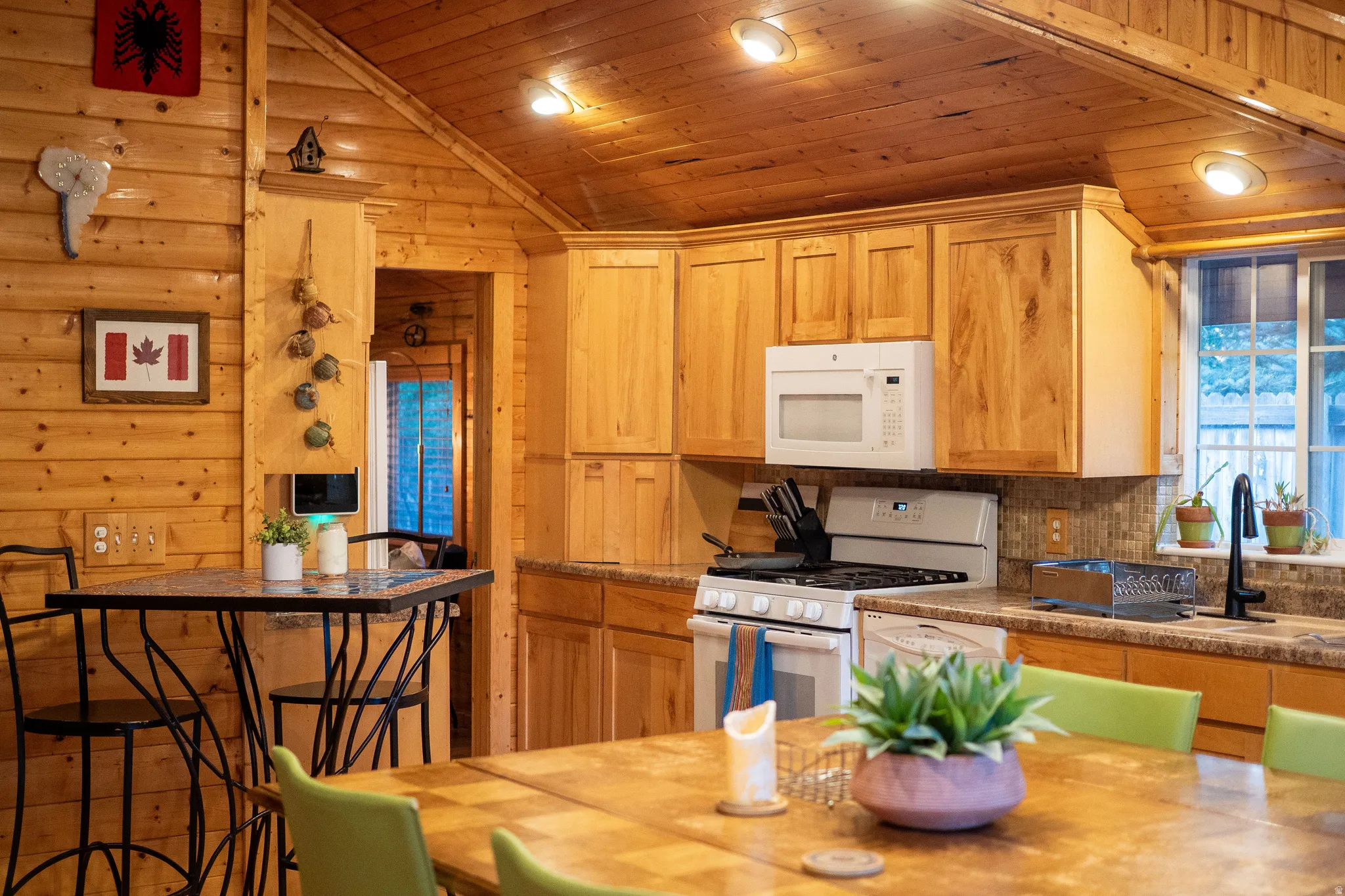 Wood-paneled walls and ceiling, recessed lighting, wood cabinetry, built-in microwave, and a gas range