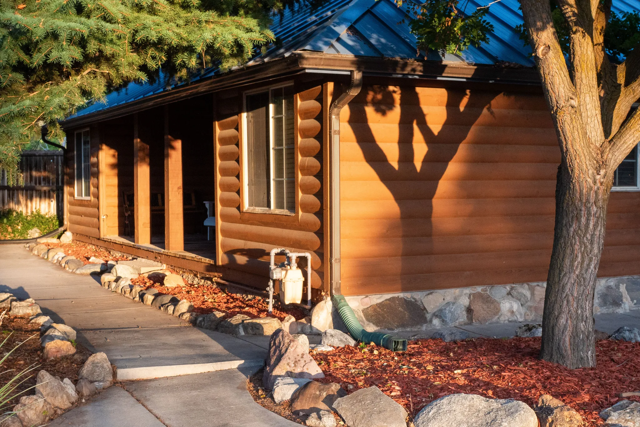 Log cabin style exterior with a blue metal roof, stone foundation, and a covered porch