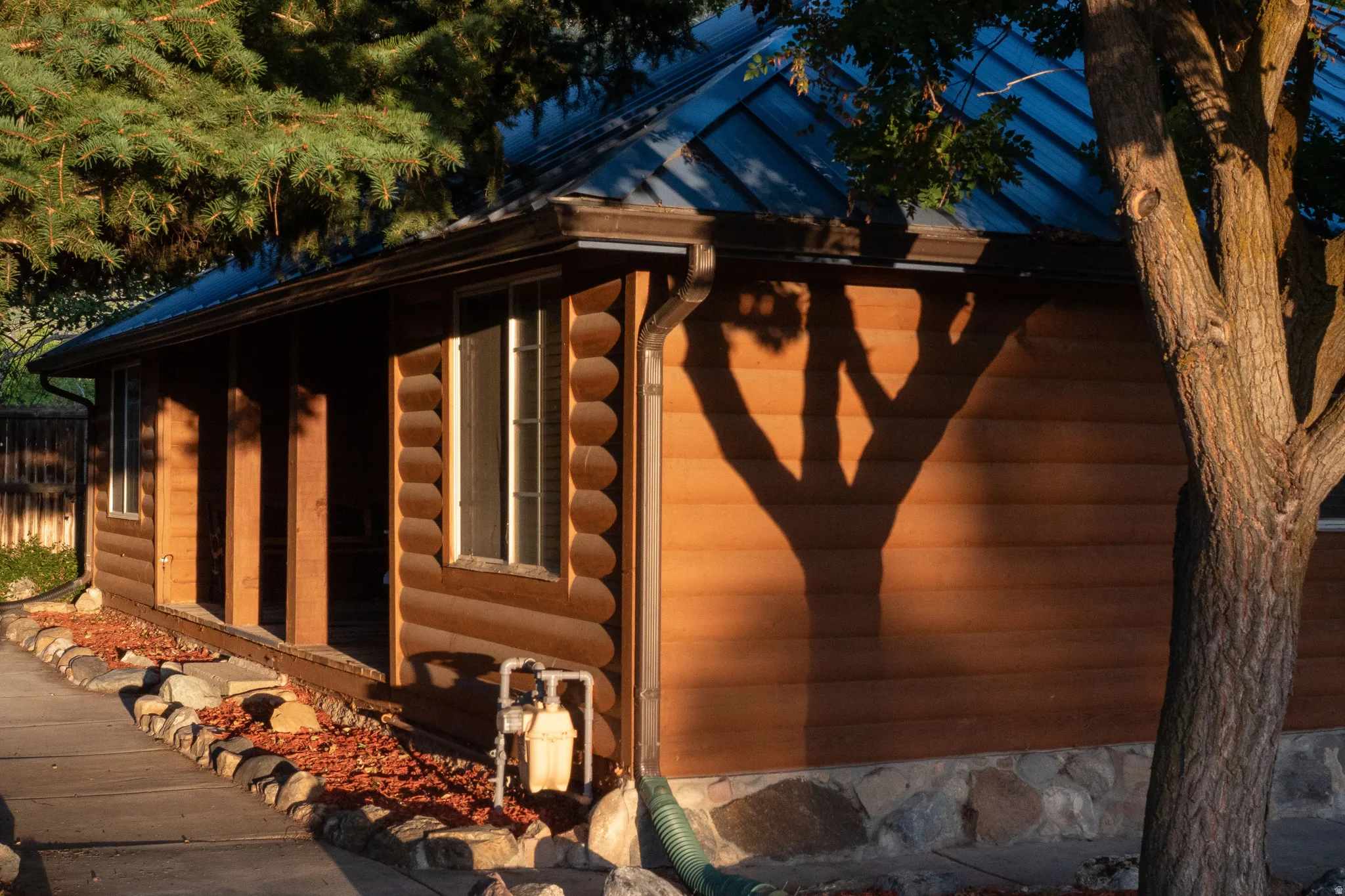 Log cabin exterior with a metal roof, covered porch, and stone foundation