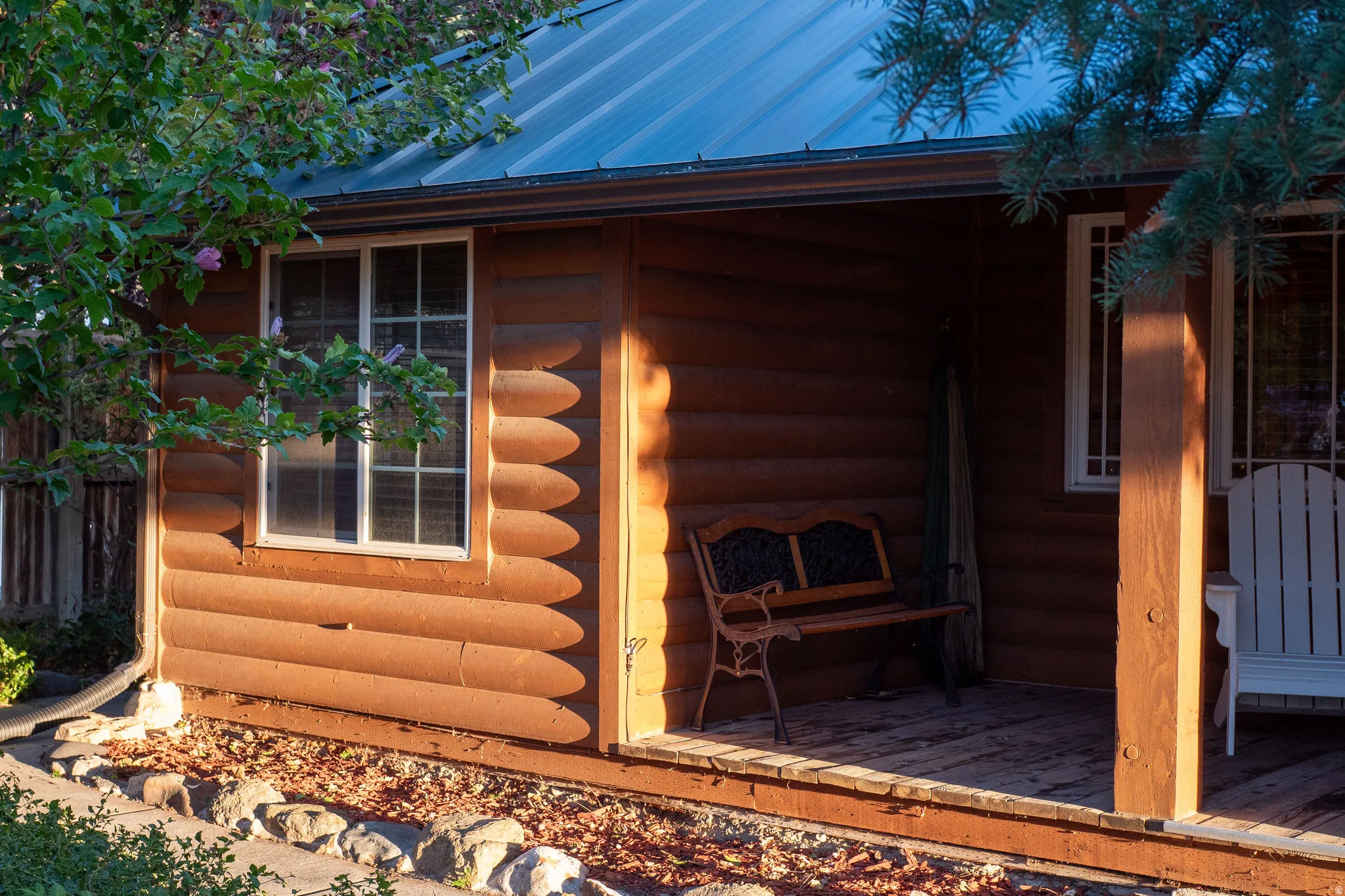 Cabin-style exterior featuring log siding, a covered porch with wood flooring, and a metal roof