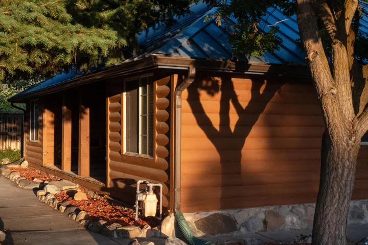 Log cabin exterior with a metal roof, covered porch, and stone foundation