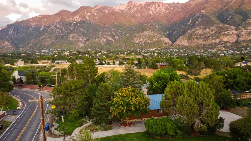Mountain backdrop, residential area, mature trees, paved road, manicured landscaping