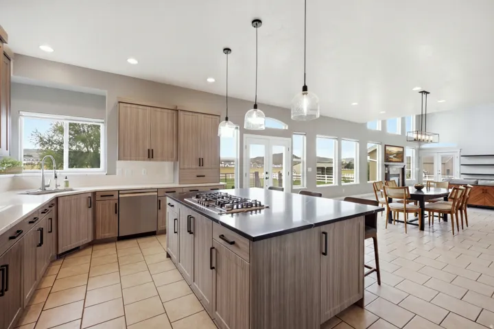 Open-concept kitchen with wood-finish cabinetry, a large center island, built-in gas cooktop, and stainless steel appliances