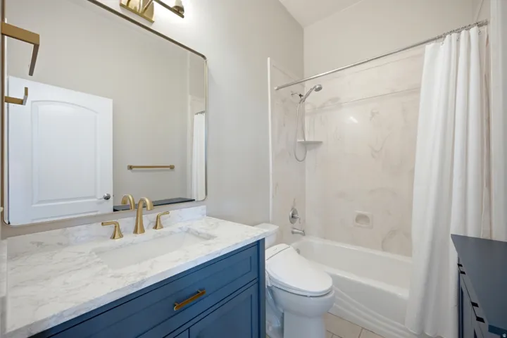 Vanity with quartz countertop, undermount sink, and brass-finish fixtures