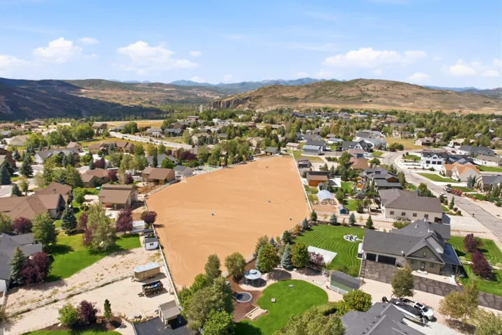 Expansive undeveloped parcel with surrounding residential properties, mountainous backdrop, and mature trees