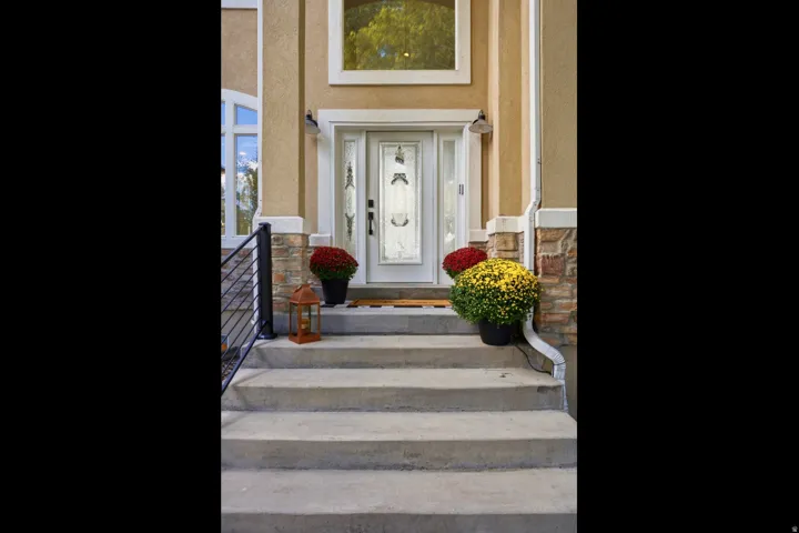 Stucco exterior with stone accents, concrete steps, and a decorative glass entry door