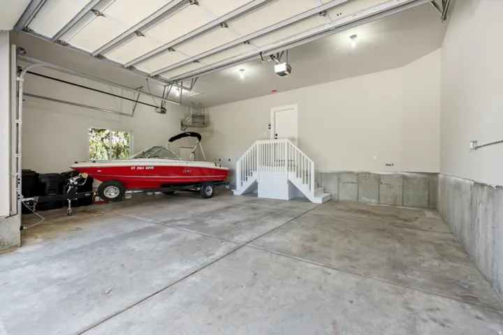 Spacious garage with concrete flooring, automatic garage doors, interior staircase, and recessed lighting