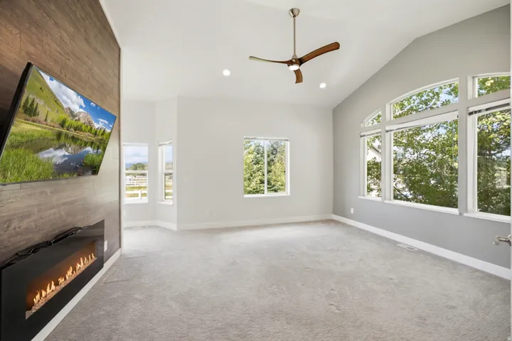 Vaulted ceiling with a contemporary ceiling fan, recessed lighting, and large arch-top windows