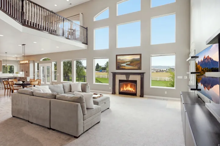 Two-story living area with multiple windows, a second-story overlook, and a fireplace with a stone surround