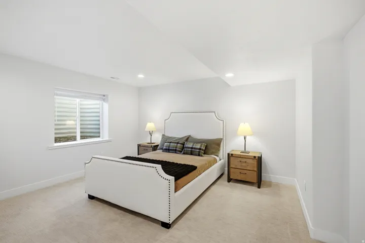 Recessed lighting illuminates neutral walls and carpeting, complemented by a window with blinds