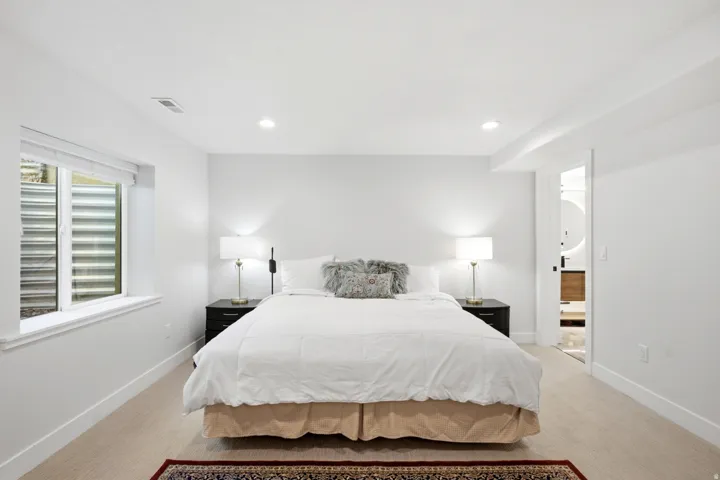 Recessed lighting, light-toned carpeting, and a window with a window well