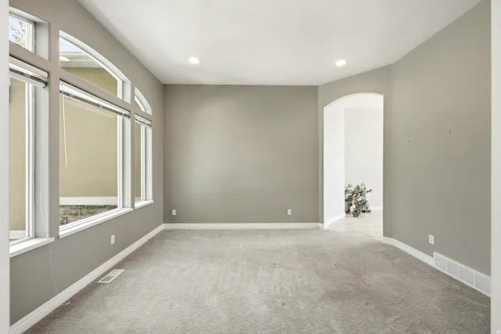 Arched window details, recessed lighting, neutral wall tones, arched doorway, and soft gray carpeting