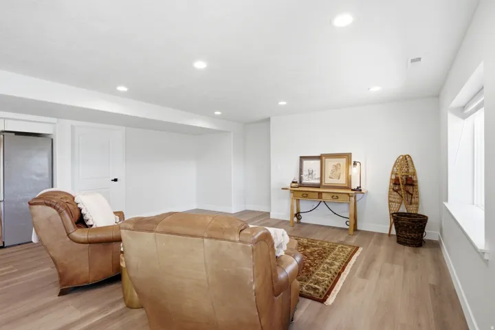 Recessed lighting, wood-finish flooring, white trim, and a window