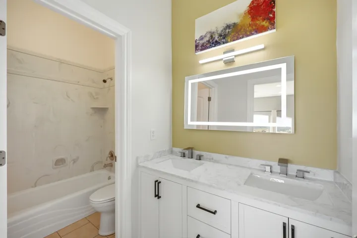 Dual sink vanity with quartz countertop, white cabinetry, and matte black hardware