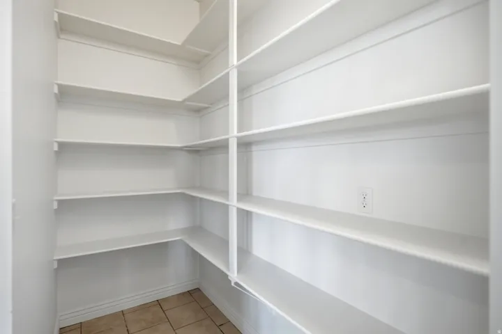 Built-in white shelving, integrated electrical outlet, and neutral-toned floor tiling