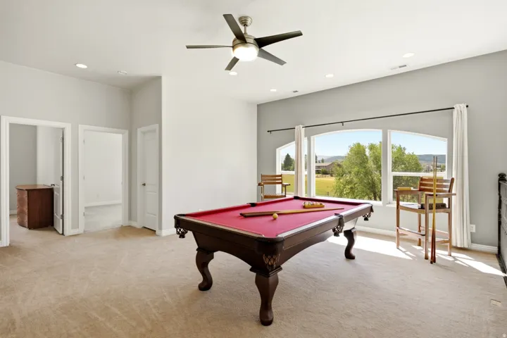 Recessed lighting, ceiling fan, arched windows, and soft carpet flooring
