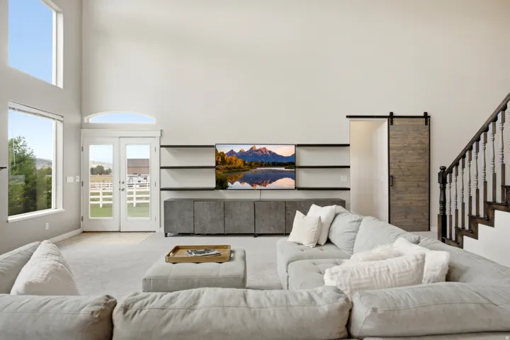 Soaring ceilings with transom window, French doors, built-in shelving, barn door access, and a dark wood staircase