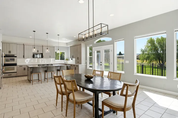 Open-concept floor plan featuring tile flooring, a kitchen island with seating, integrated double ovens, and expansive windows