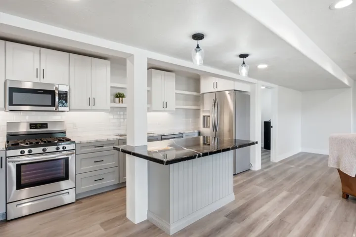Kitchen featuring stainless steel appliances, light-toned cabinetry, dark countertops, a white subway tile backsplash, and recessed lighting