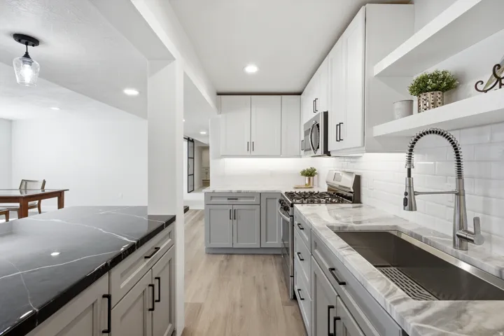 Kitchen featuring light gray lower cabinetry, white upper cabinetry, stainless steel appliances, a stainless steel sink, and light wood-finish flooring