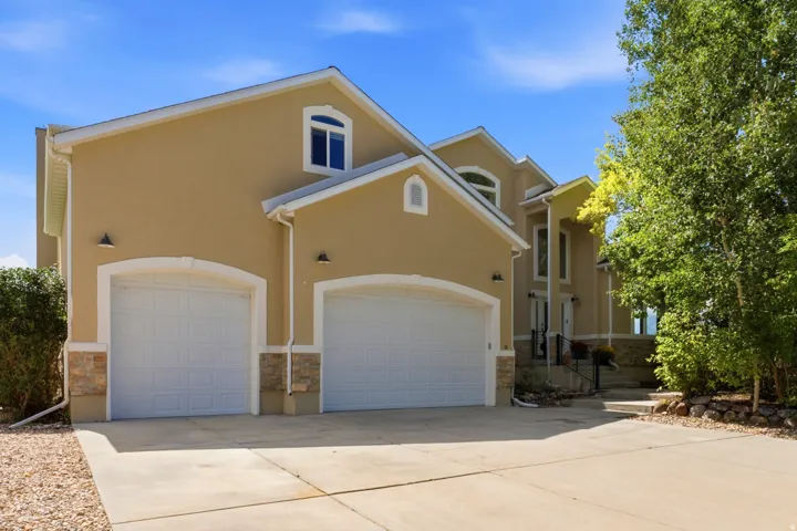 Stucco exterior with stone accents, two-car garage, arched garage door openings, arched windows, and a concrete driveway