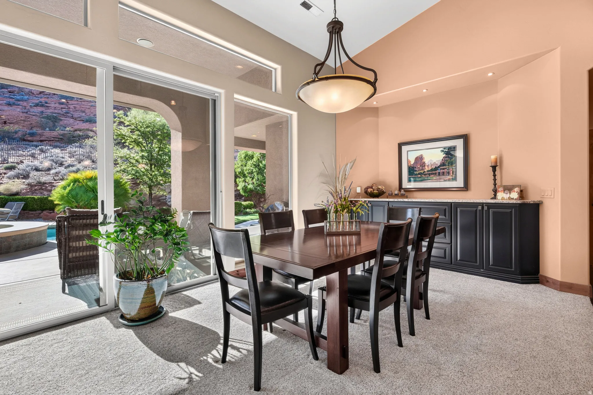 Vaulted ceiling, built-in cabinetry with a stone countertop, sliding glass doors, transom windows, and recessed lighting