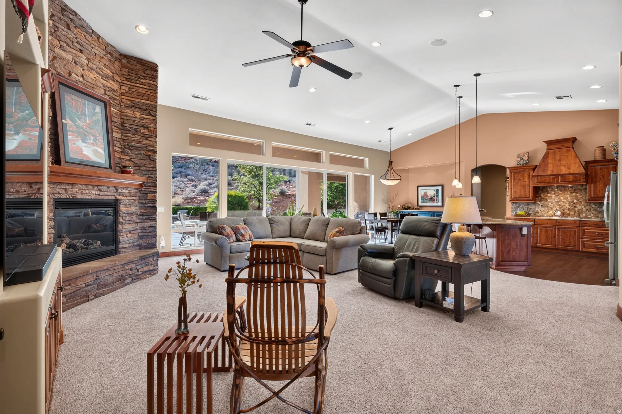 Spacious living area with vaulted ceilings, a stone-clad fireplace, and large sliding glass doors