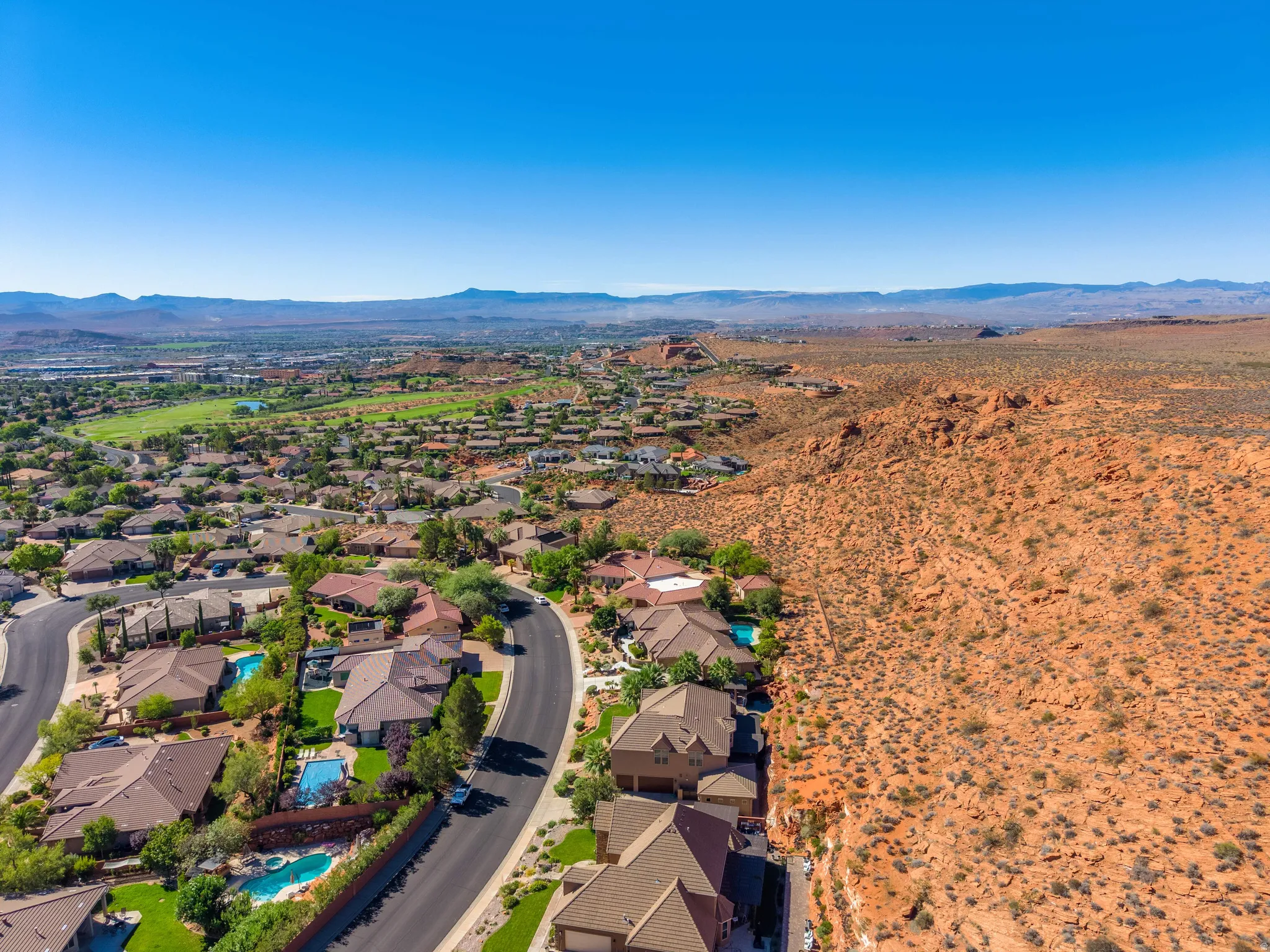 Residential neighborhood with curved streets, multiple homes featuring private pools, and a golf course