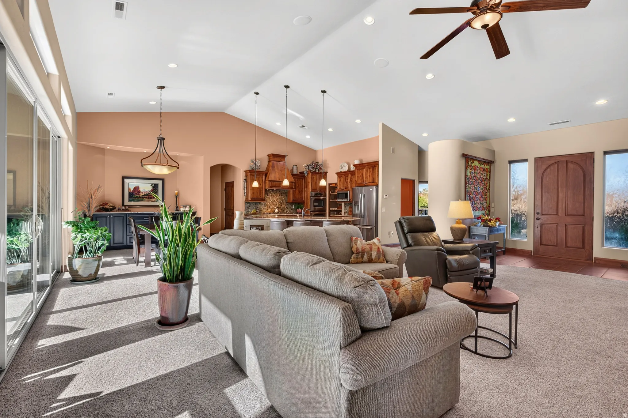 Vaulted ceiling with recessed lighting, ceiling fan, and large sliding glass doors