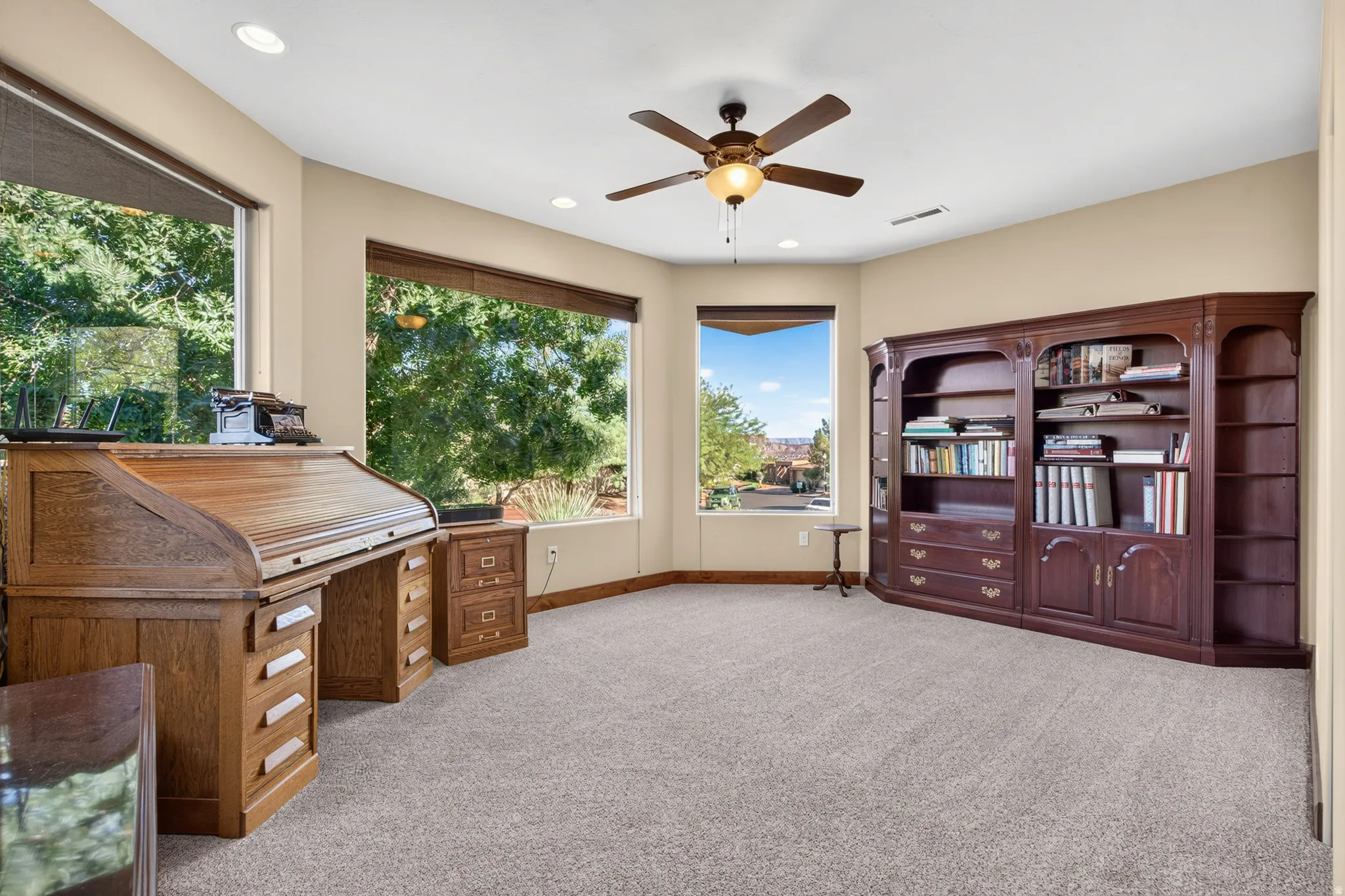 Recessed lighting, ceiling fan, expansive windows, built-in wooden shelving, and wall-to-wall carpeting
