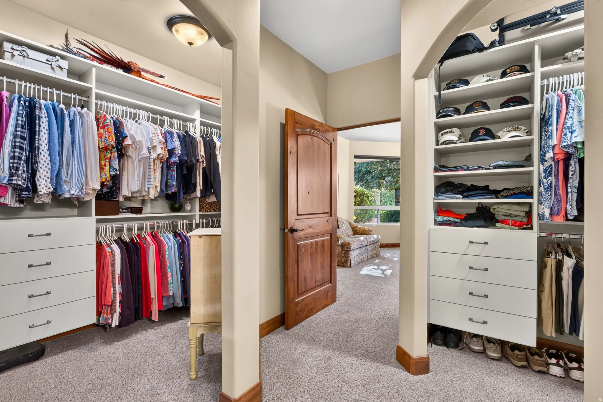 Walk-in closet featuring built-in shelving, integrated drawers, hanging rods, and an arched entry