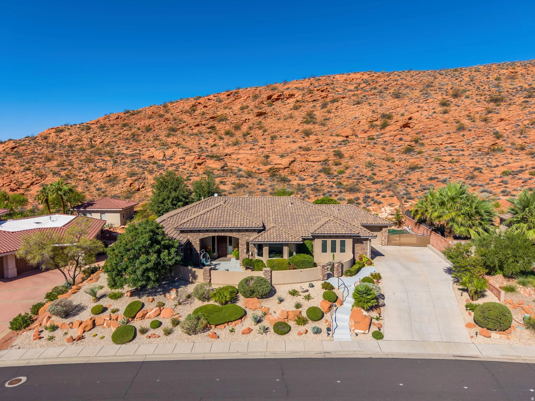 Mediterranean-style architecture with a tile roof, desert landscaping, and a paved driveway